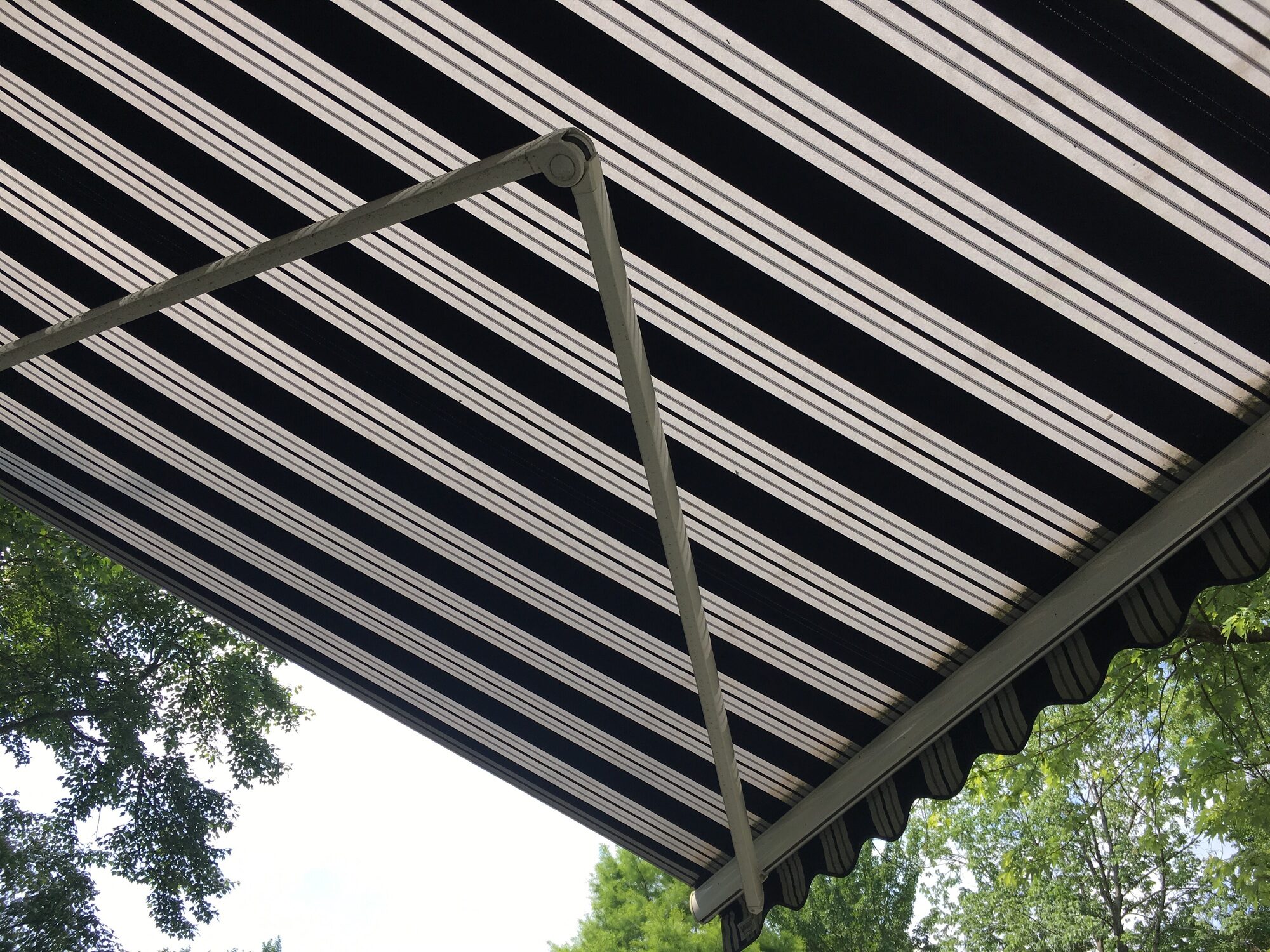Blue and white striped folding umbrella above patio outdoors